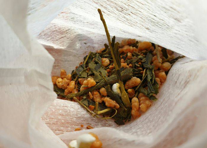 A peek inside a bag of genmaicha tea, filled with green tea leaves, roasted brown rice and popped rice kernels.
